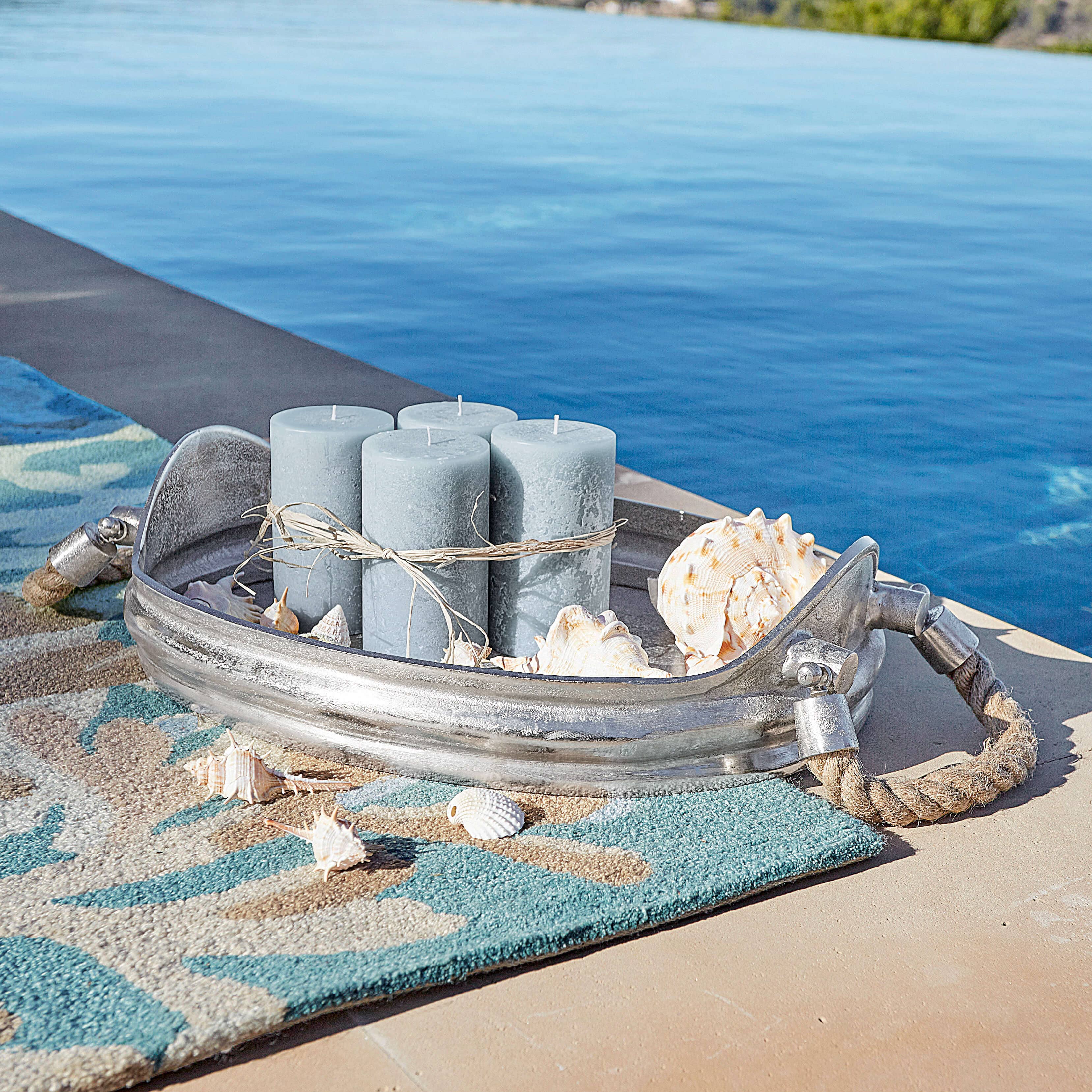 Ovale Aluminiuguss-Schale in Silber mit Seilgriffen, blauen Kerzen und Muscheldekor am Poolrand