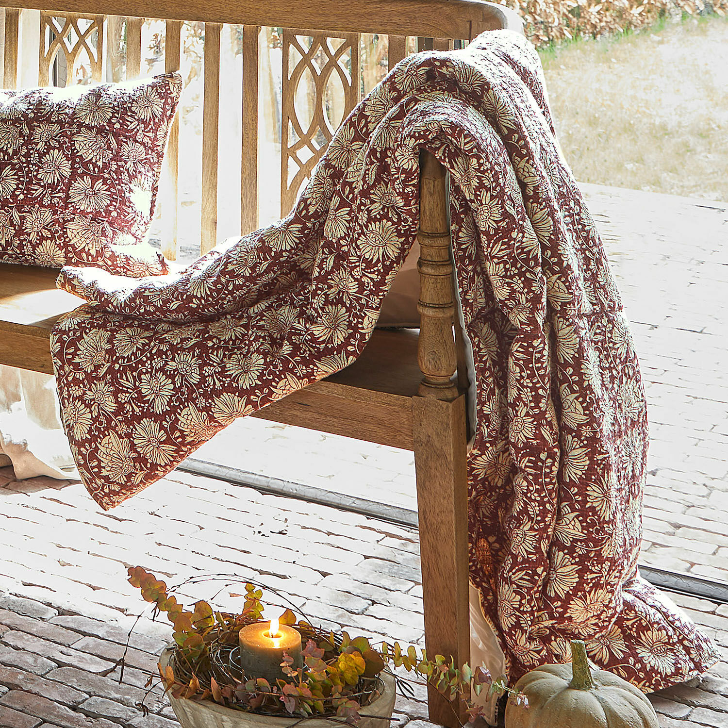 Plaid Soleique Rote Decke und Kissen mit Blumenmuster auf Holzbank, herbstliche Dekoration mit Kürbis und Kerze