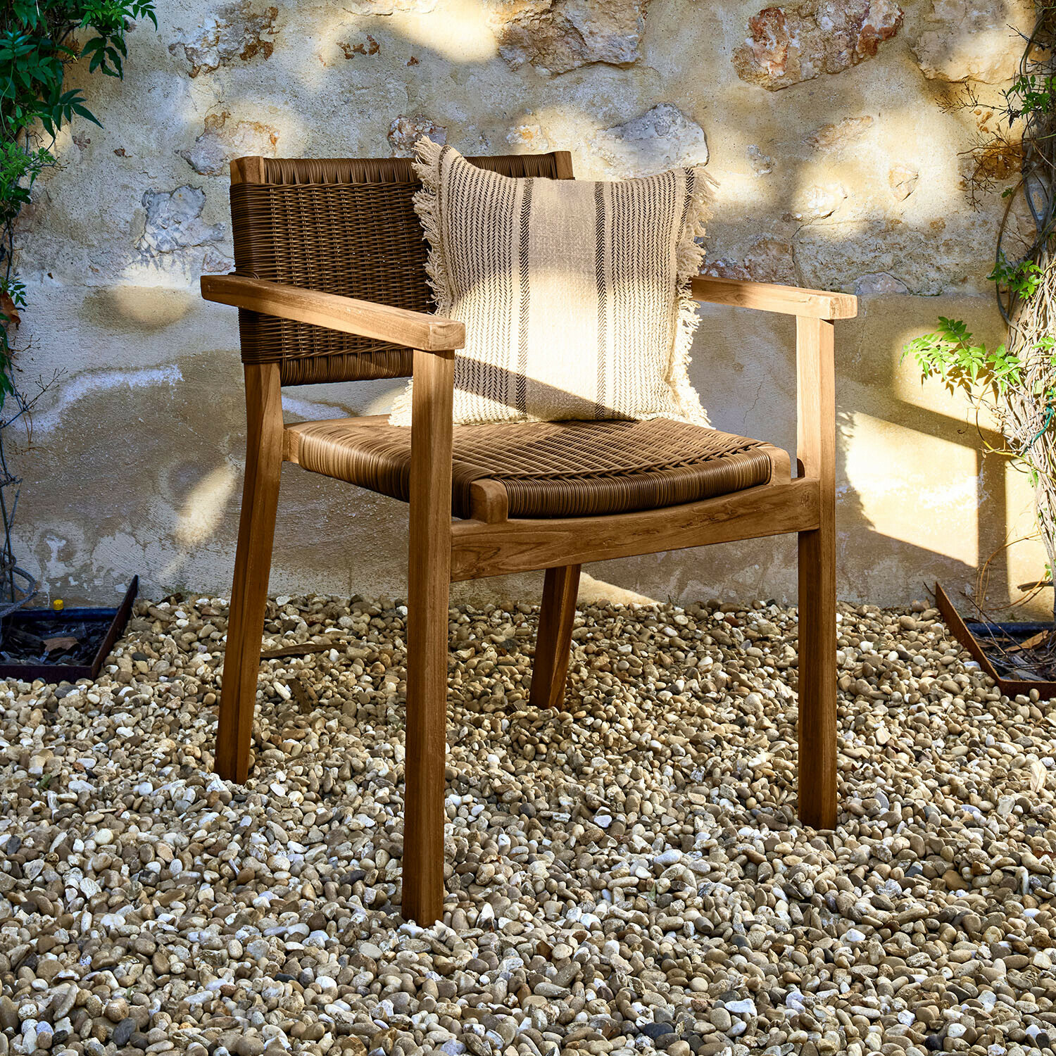 Stuhl Calvini Gartenstuhl aus Holz und Rattan in Naturfarben mit Zierkissen auf hellem Kiesboden