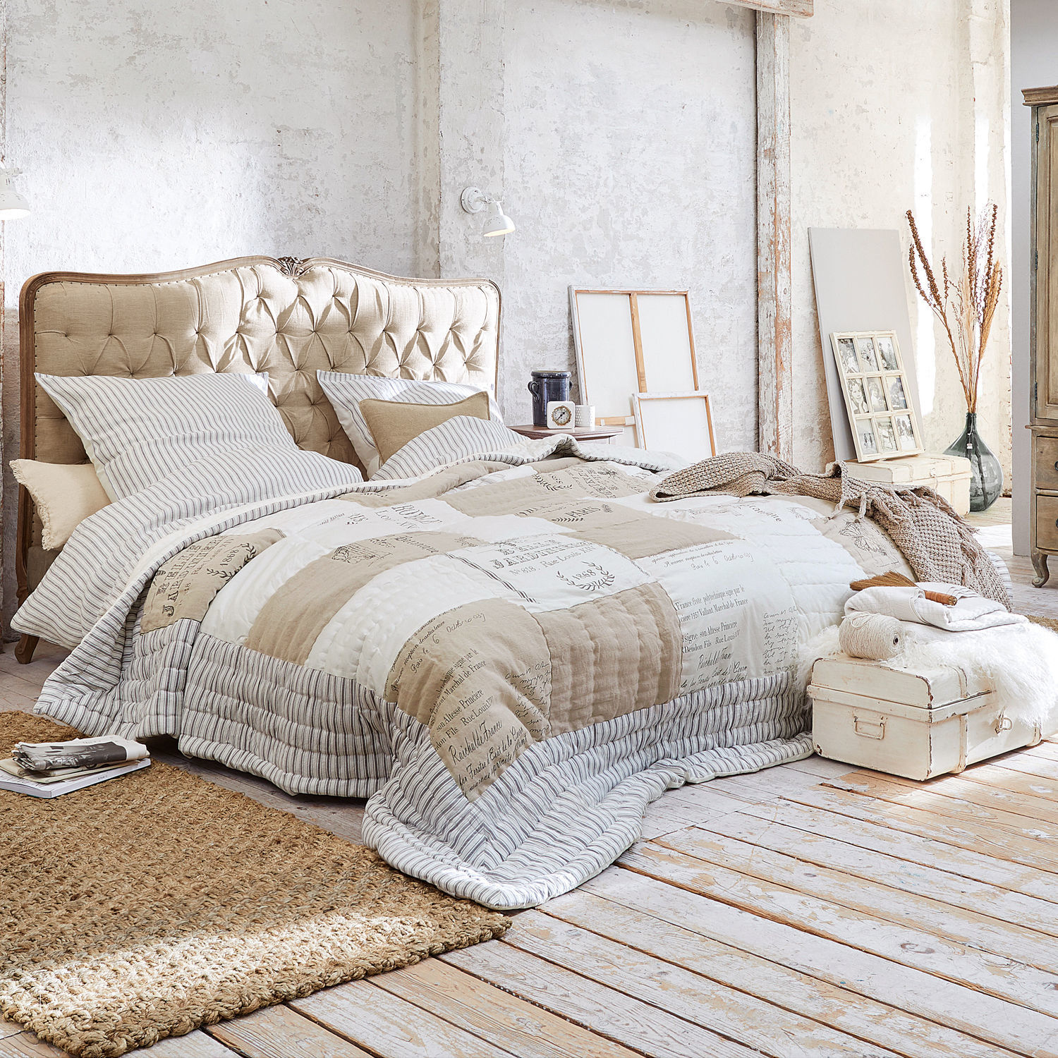 Quilt Framingham Gemütliches Schlafzimmer mit beigem, gepolstertem Kopfteil und Patchwork-Steppdecke in Naturtönen.
