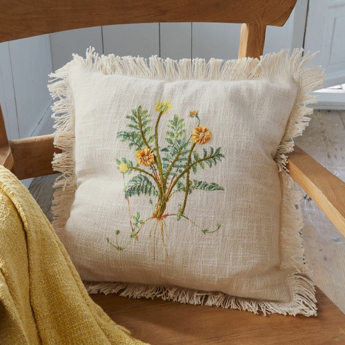 Beiges Leinenkissen mit Fransen und besticktem Blumenmotiv auf Holzstuhl