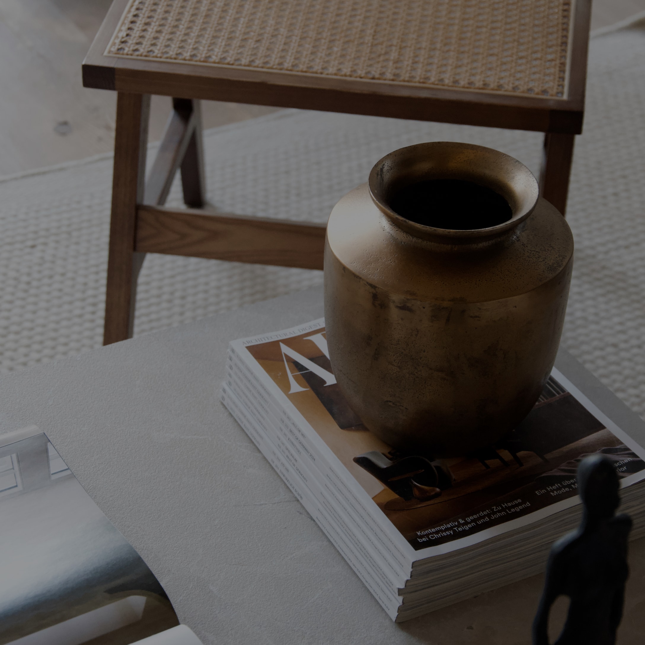 Dekorative Messingvase auf einem Stapel Zeitschriften auf hellem Tisch in modernem Interieur