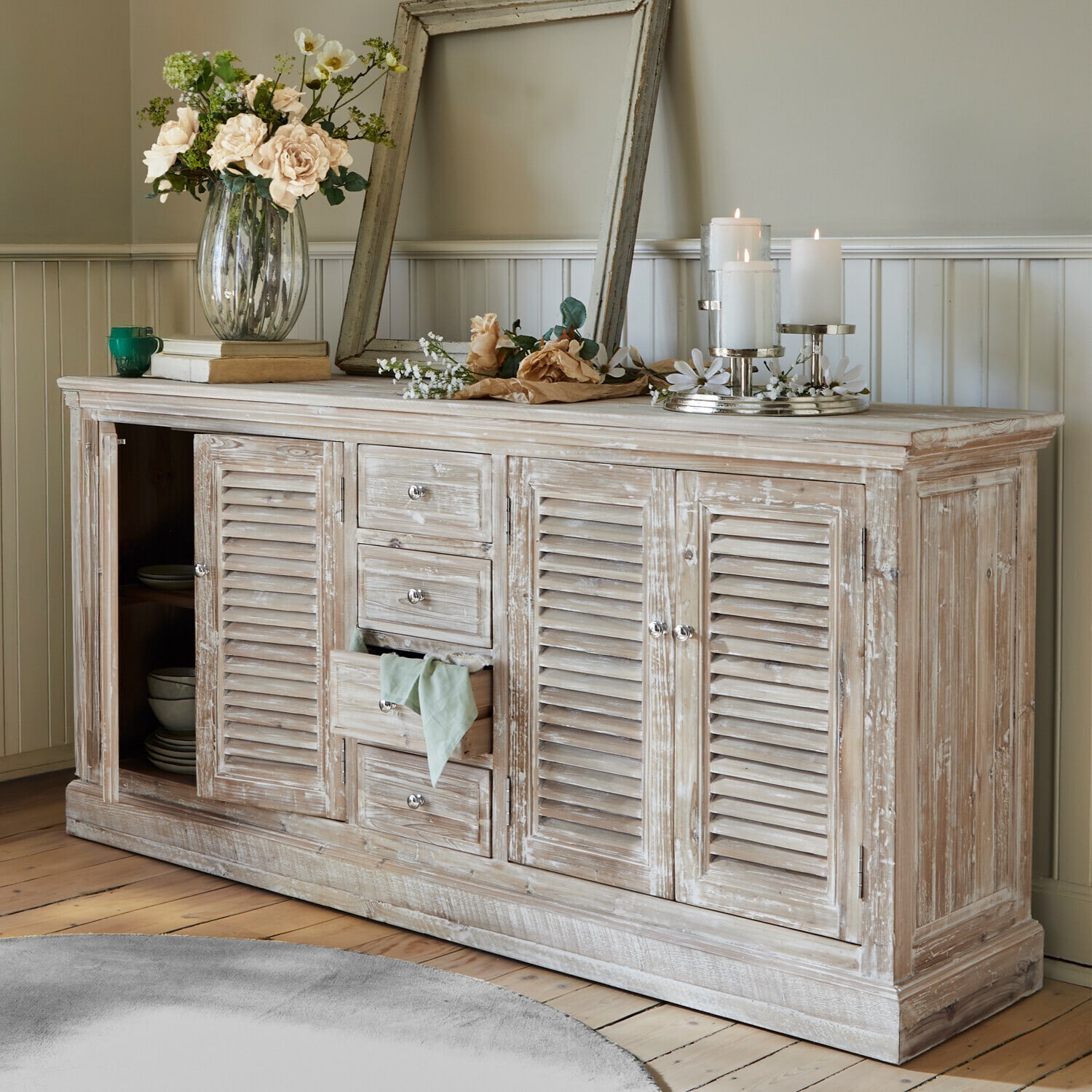 Rustikales Sideboard aus Holz mit weiss gewischtem Finish, Dekorationen und Kerzen im Wohnzimmer