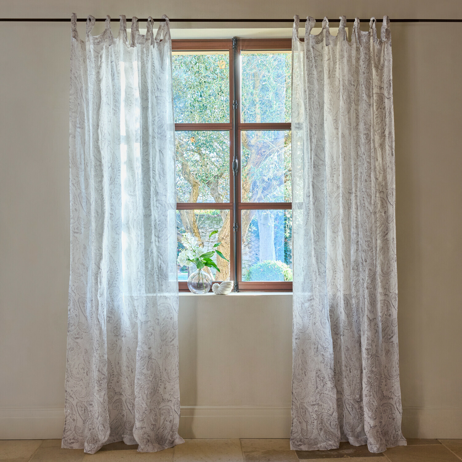 Transparente weisse Vorhänge mit feinem Paisley-Muster am Fenster, helle Wohnraumdekoration