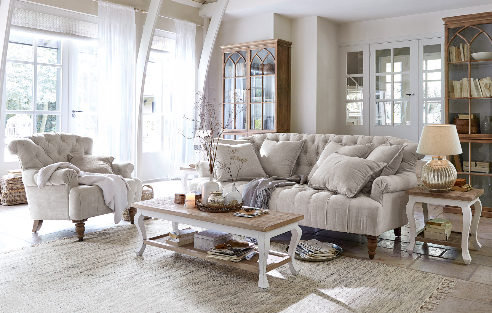 Gemütliches Wohnzimmer im Landhausstil mit beigem Stoffsofa, Sessel und hellen Holzmöbeln
