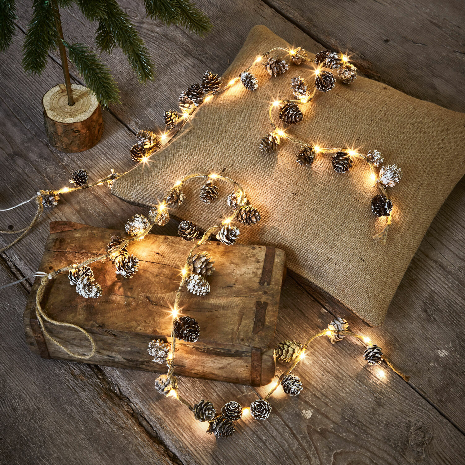 Lichterkette 2er Set Crane Lichterkette mit Tannenzapfen und warmem Licht dekorativ auf Holztisch und Leinenkissen drapiert