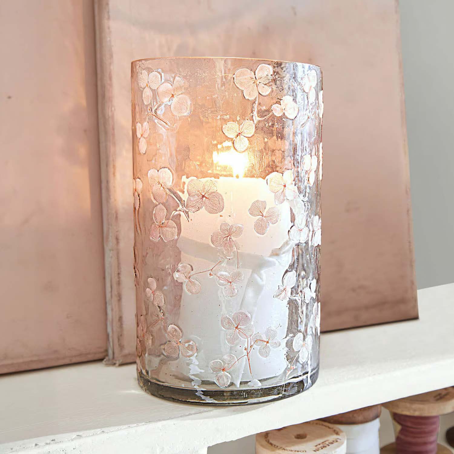 Glaswindlicht mit weissen Blumenmustern und brennender Kerze, elegante Wohnraumdekoration