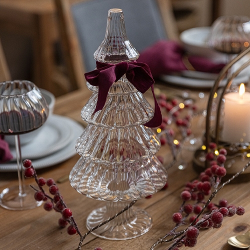 Glas-Weihnachtsbaumschmuck mit bordeauxroter Schleife auf Holztisch mit Weihnachtsdekoration