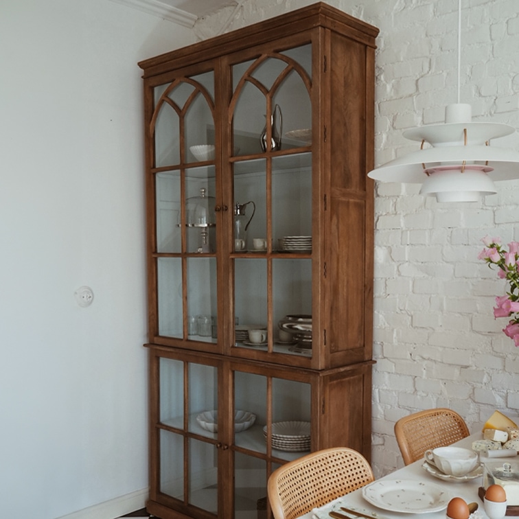 Holzvitrine mit verglasten Türen im Vintage-Stil in einem Esszimmer mit weisser Ziegelwand