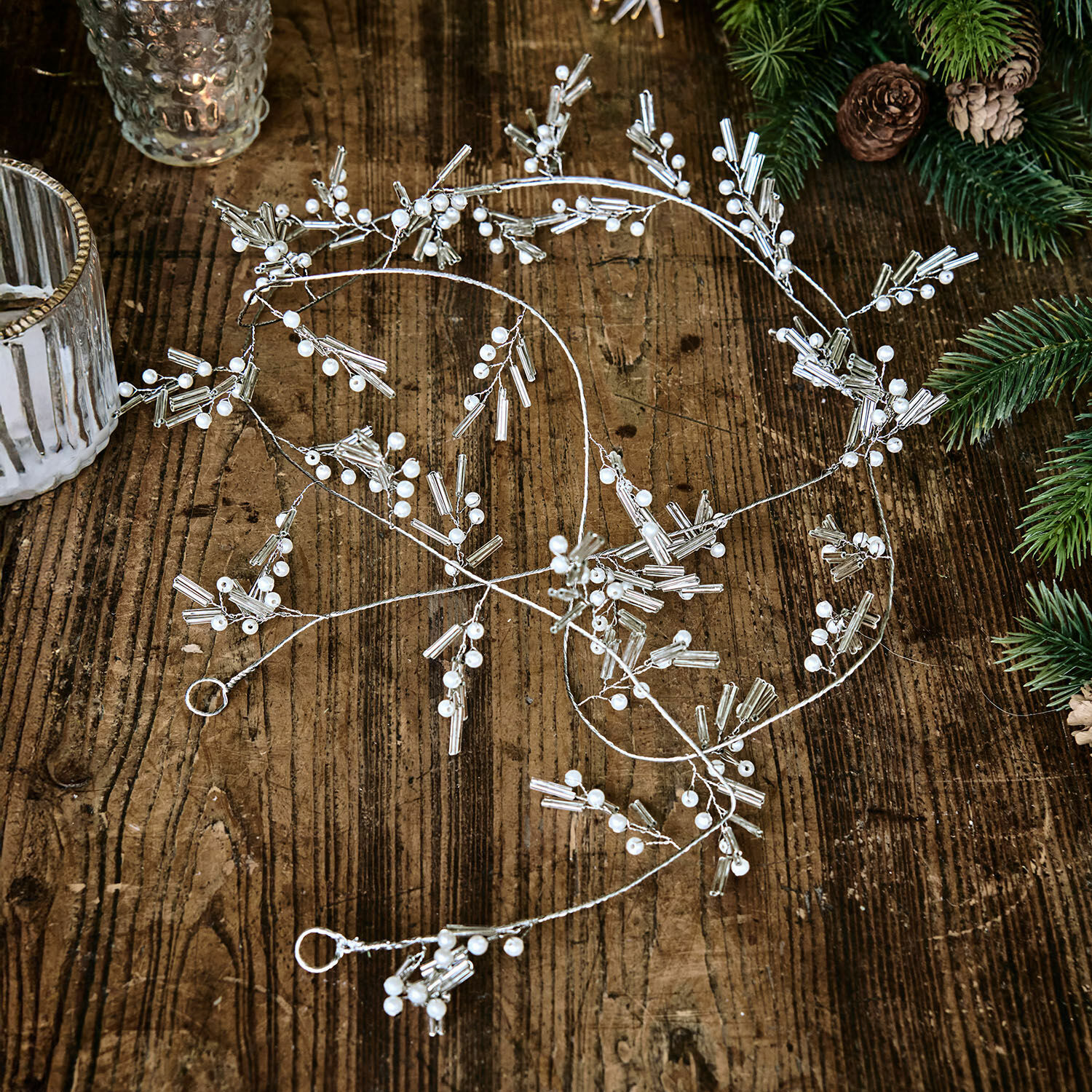 Girlande Hybern Feine silberne Dekokette mit weissen Perlen auf Holztisch, festliche Weihnachtsdekoration