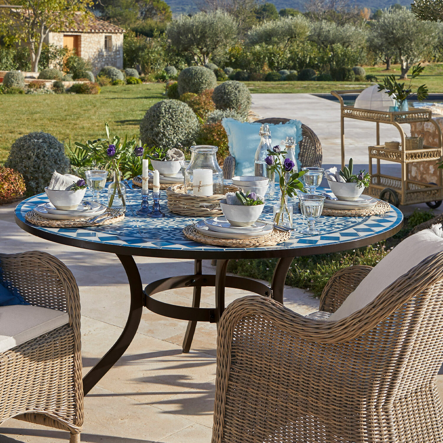 Tisch Jennarton Runder Gartentisch mit blau-weisser Mosaik-Tischplatte und Rattanstühlen auf der Terrasse