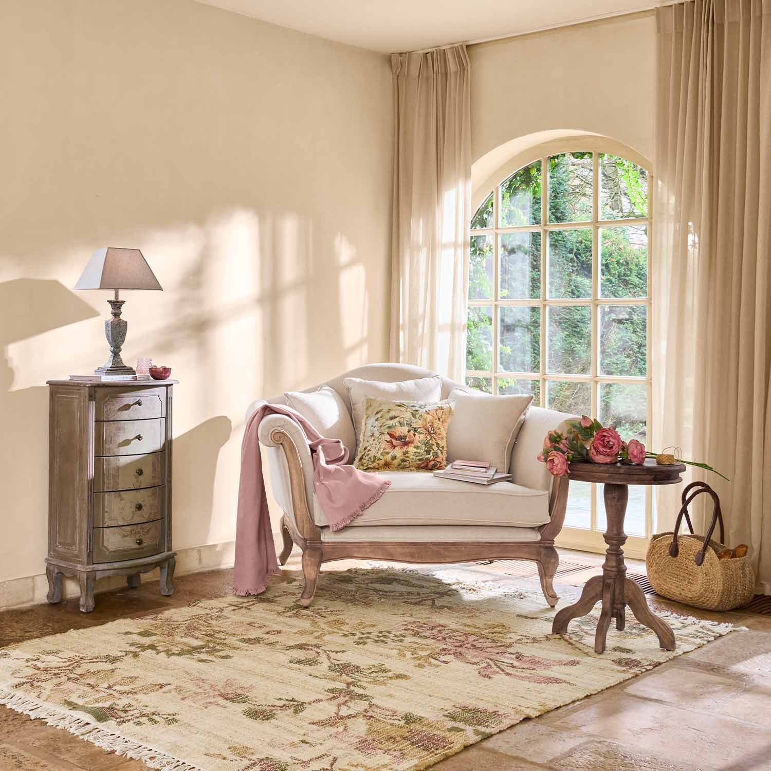 Gemütlicher Sessel aus hellem Holz und cremefarbenem Stoff mit Kissen und rosa Decke im Wohnzimmer