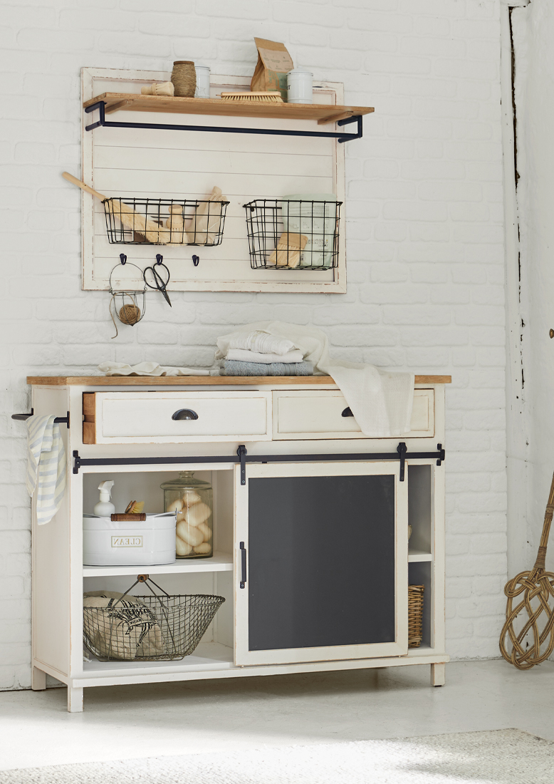 Weißer Holzschrank mit schwarzer Schiefertafel und Metallkörben an der Wand, rustikaler Stil