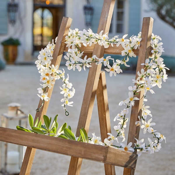 Holzstaffelei mit weisser Blumen- und grüner Blattdekoration im Aussenbereich, Gartendekor