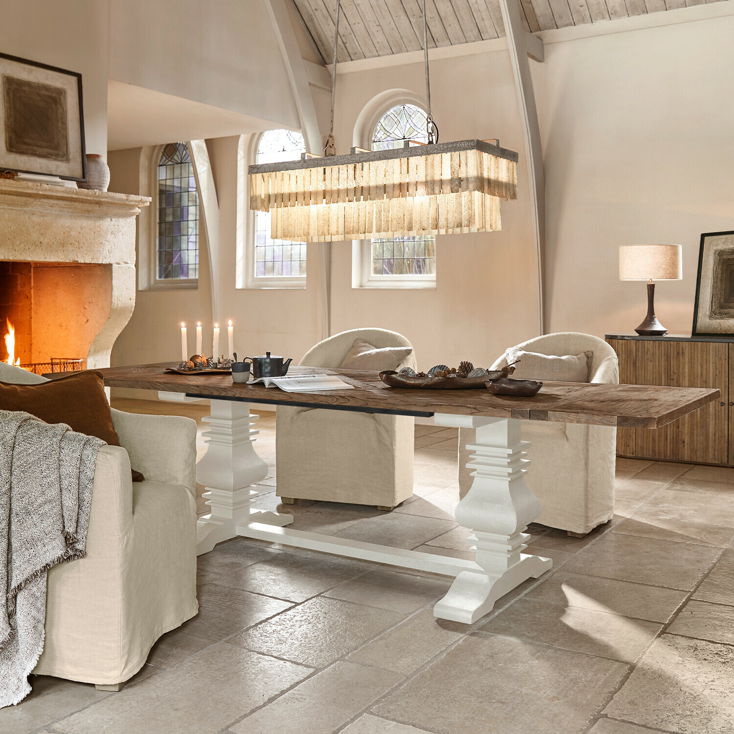 Großer Holztisch mit weissem Untergestell in hellem Wohnzimmer mit Kamin und beigen Sesseln