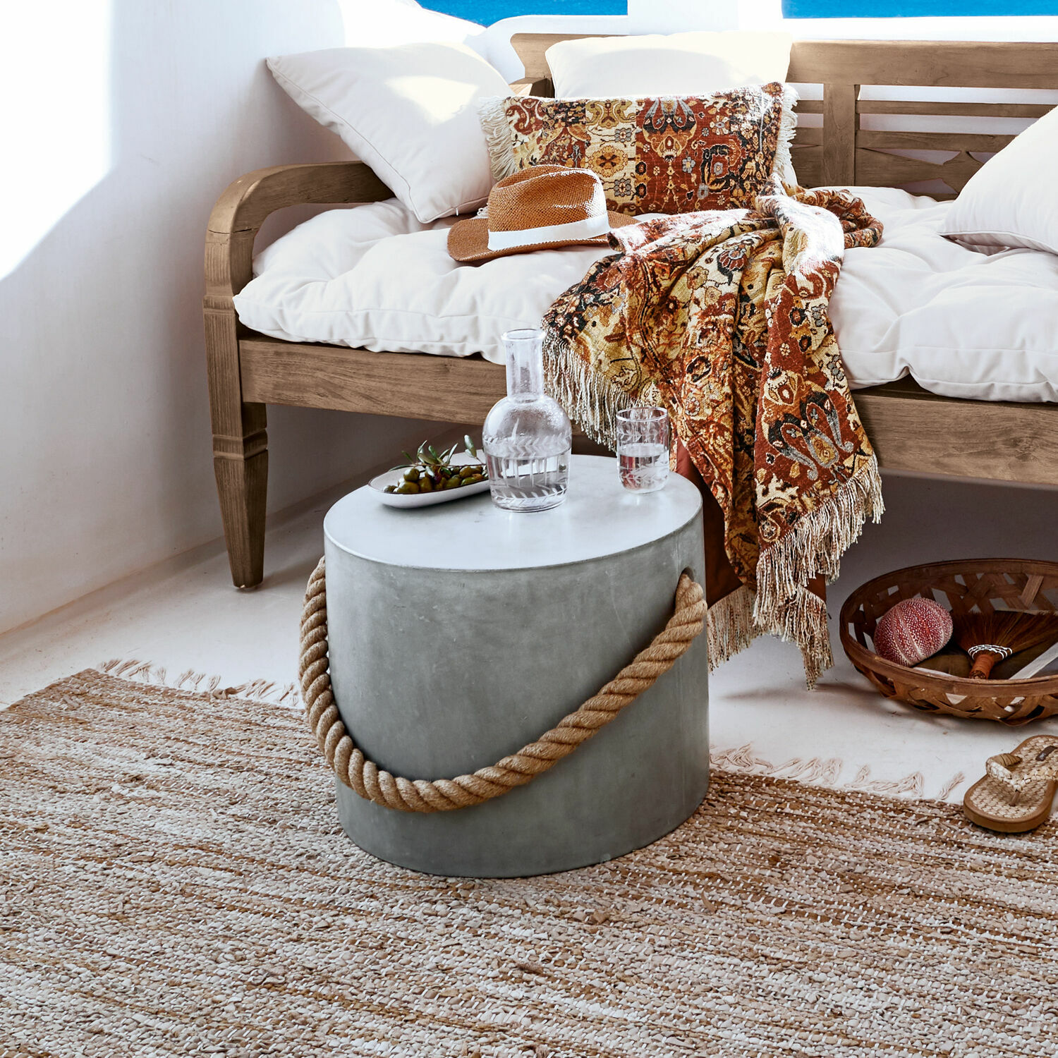Runder Beistelltisch aus Beton mit Hanfseilgriff im natürlichen Wohnzimmer mit Holzsofa und dekorativer Decke