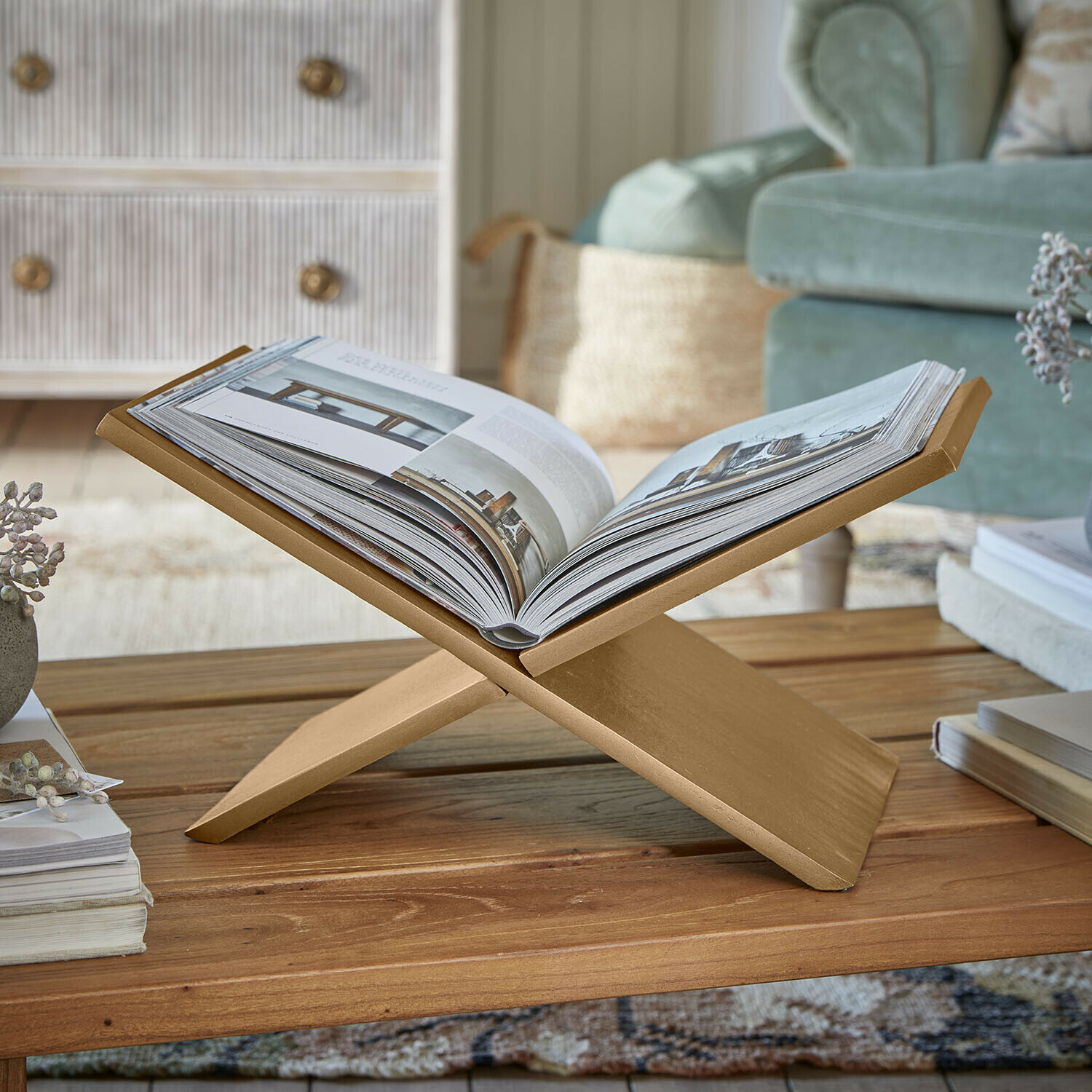 Zeitschriftenständer Rashira Goldener Holzbuchhalter auf Couchtisch in gemütlichem Wohnzimmer mit grünem Sofa