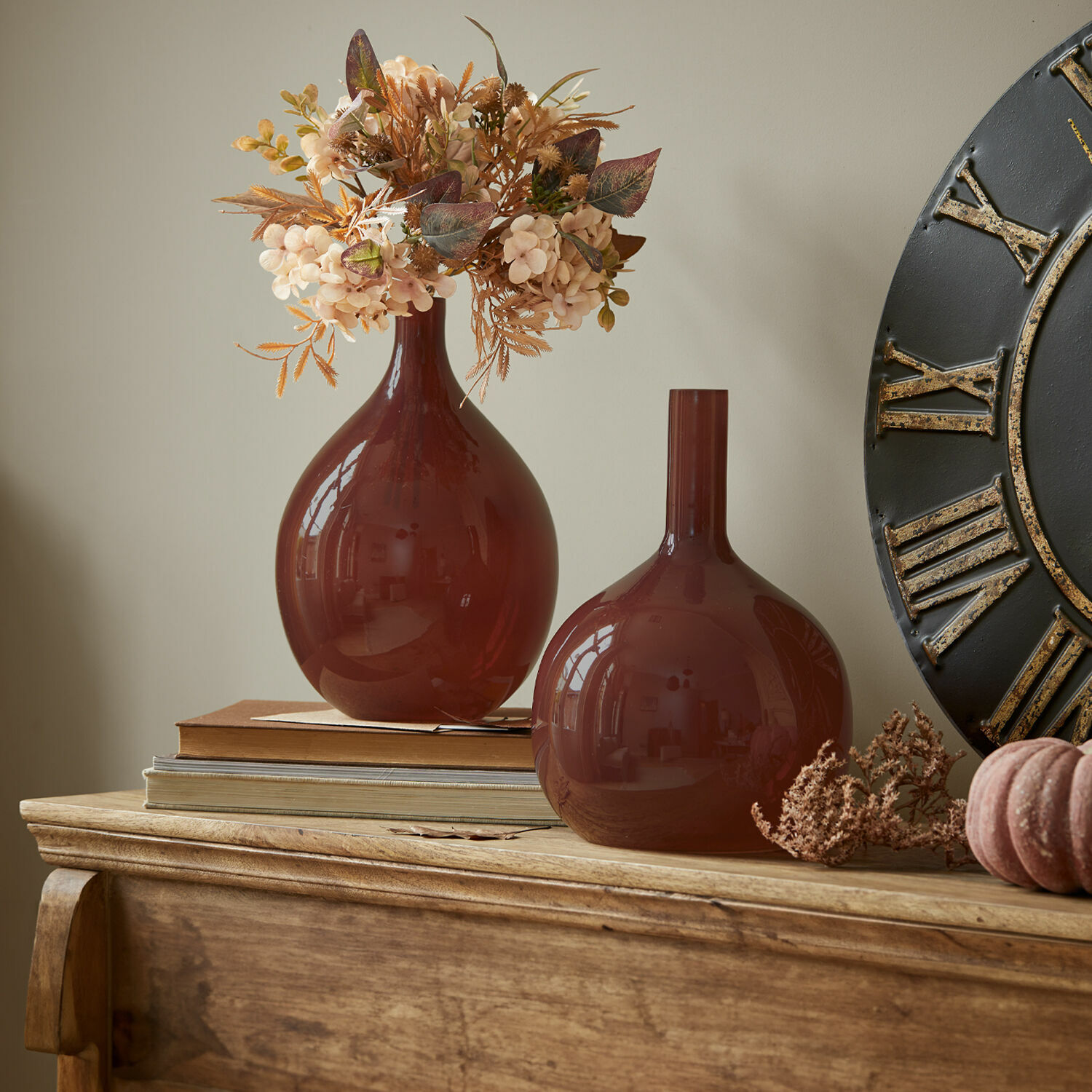 Vase 2er Set Erlunda Zwei braune Glasvasen auf einer Holzkommode mit dekorativen Trockenblumen und Büchern