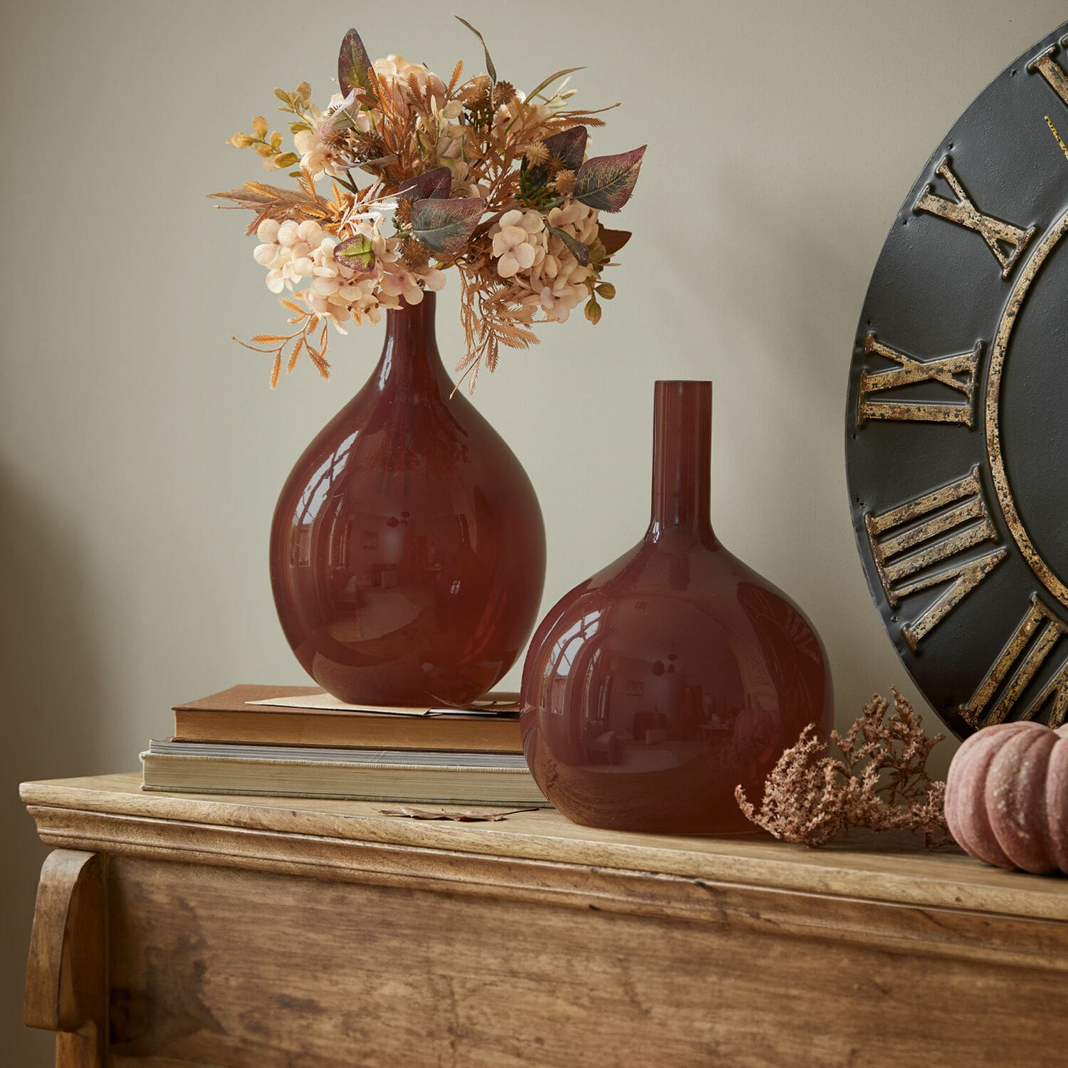 Vase 2er Set Erlunda Zwei braune Glasvasen auf einer Holzkommode mit dekorativen Trockenblumen und Büchern