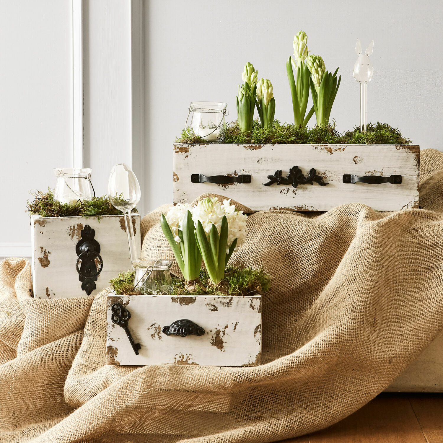 Rustikale weisse Holzkisten mit grünen und weissen Hyazinthenblüten und dekorativem Moos