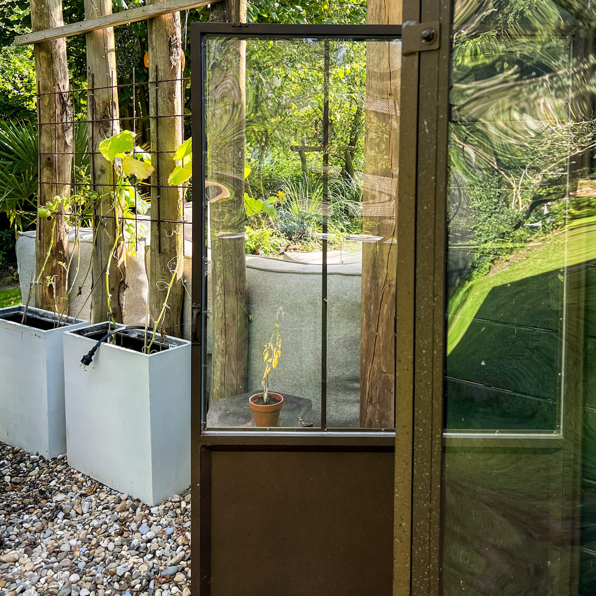 Gartentür mit Glas und Metallrahmen vor Pflanzen und Kies, moderner Stil