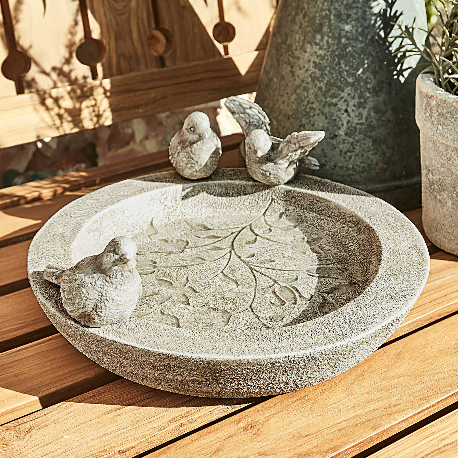 Vogelbad Joalien Dekorative graue Steinschale mit Blattmotiv und drei Vögeln auf Holztisch im Garten