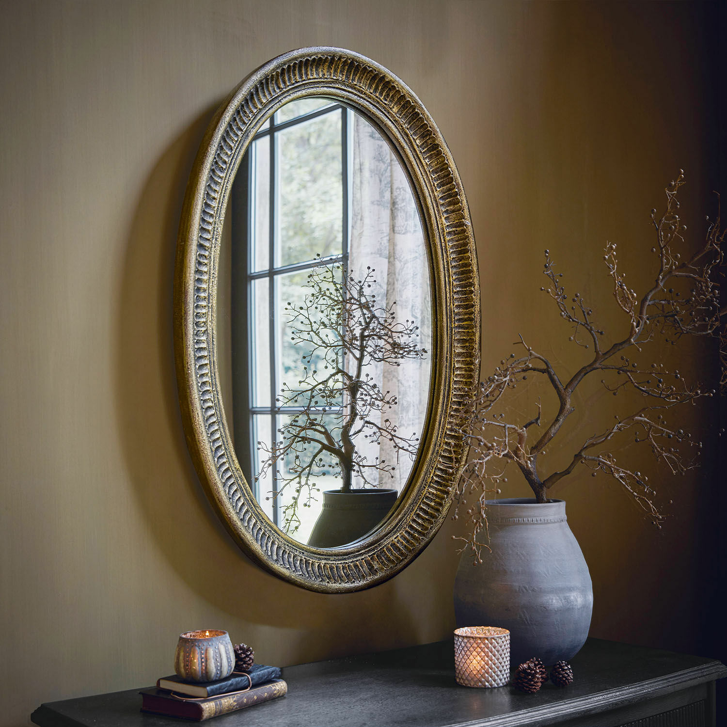 Spiegel Boissiére Ovals Spiegel mit antik-goldenem Rahmen an der Wand, dekorierter Tisch mit Vase und Kerzen