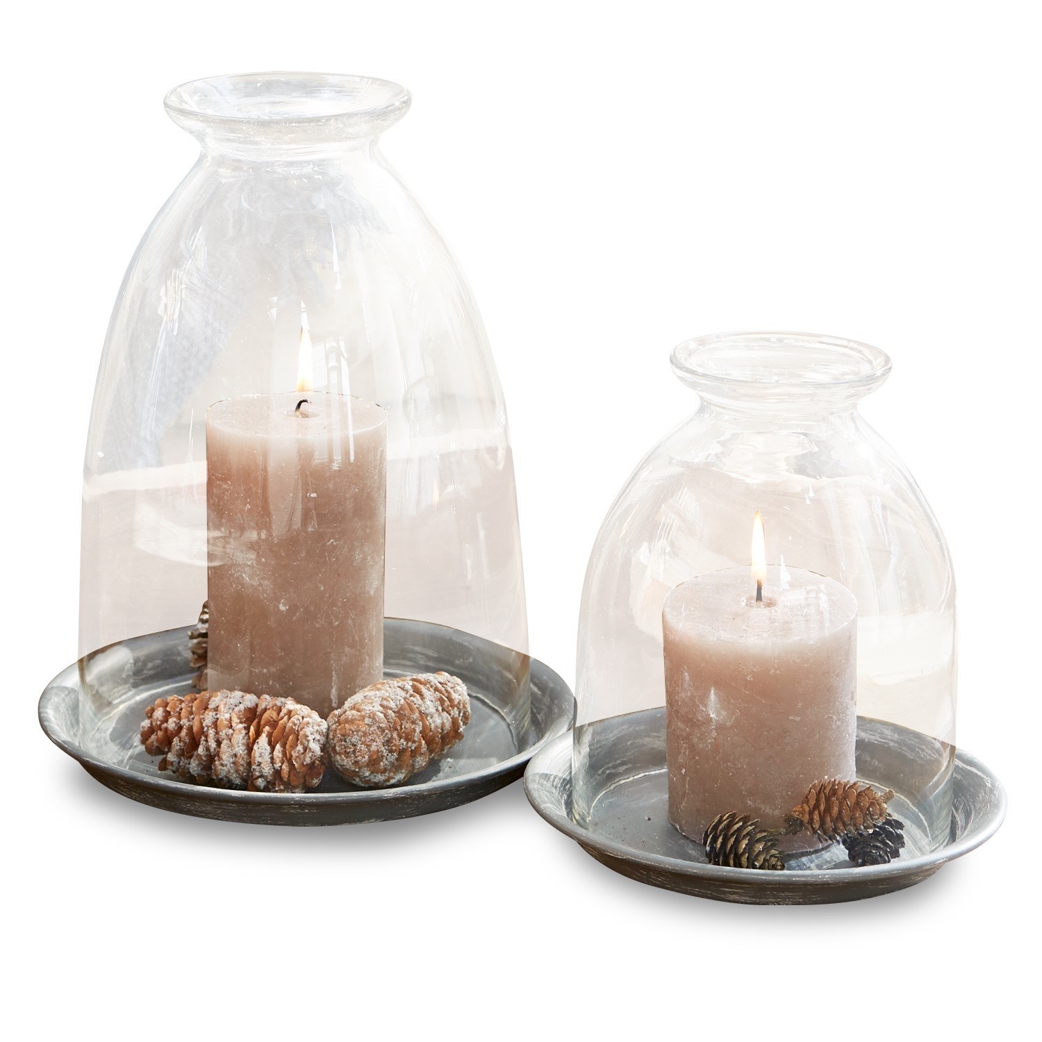 Set aus zwei Kerzen unter Glasglocken auf Metallplatten mit dekorativen Zapfen