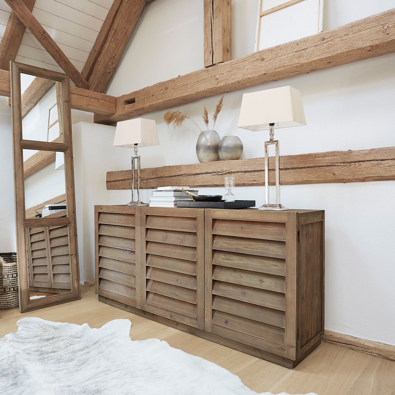 Kommode Lens Rustikale Holzkommode mit Lamellentüren in Naturfarbe, dekoriert mit Tischlampen und Vasen im Wohnzimmer