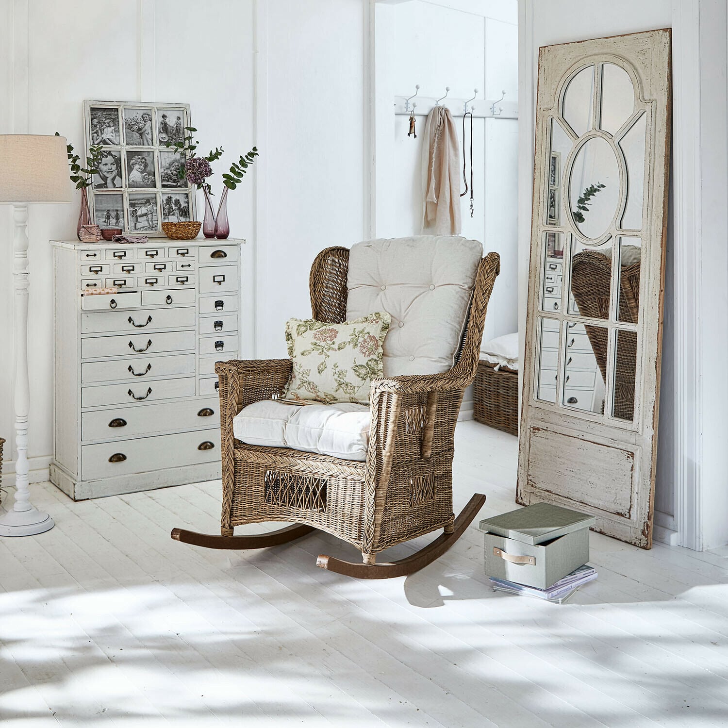 Schaukelstuhl Jeveren Rattanschaukelstuhl mit cremefarbenen Polstern in hellem Zimmer mit weissem Holzboden