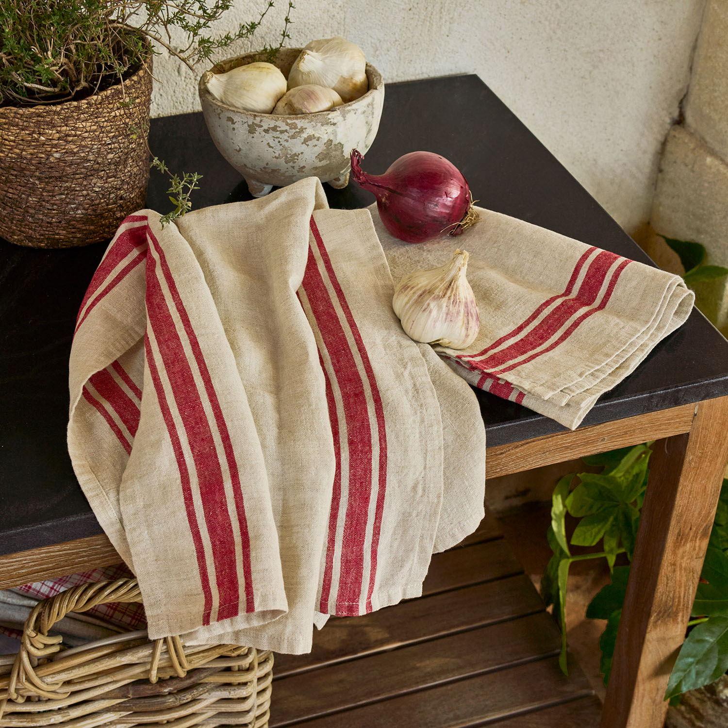 Beiges Leinen-Geschirrtuch mit roten Streifen auf einem Holztisch mit schwarzer Platte