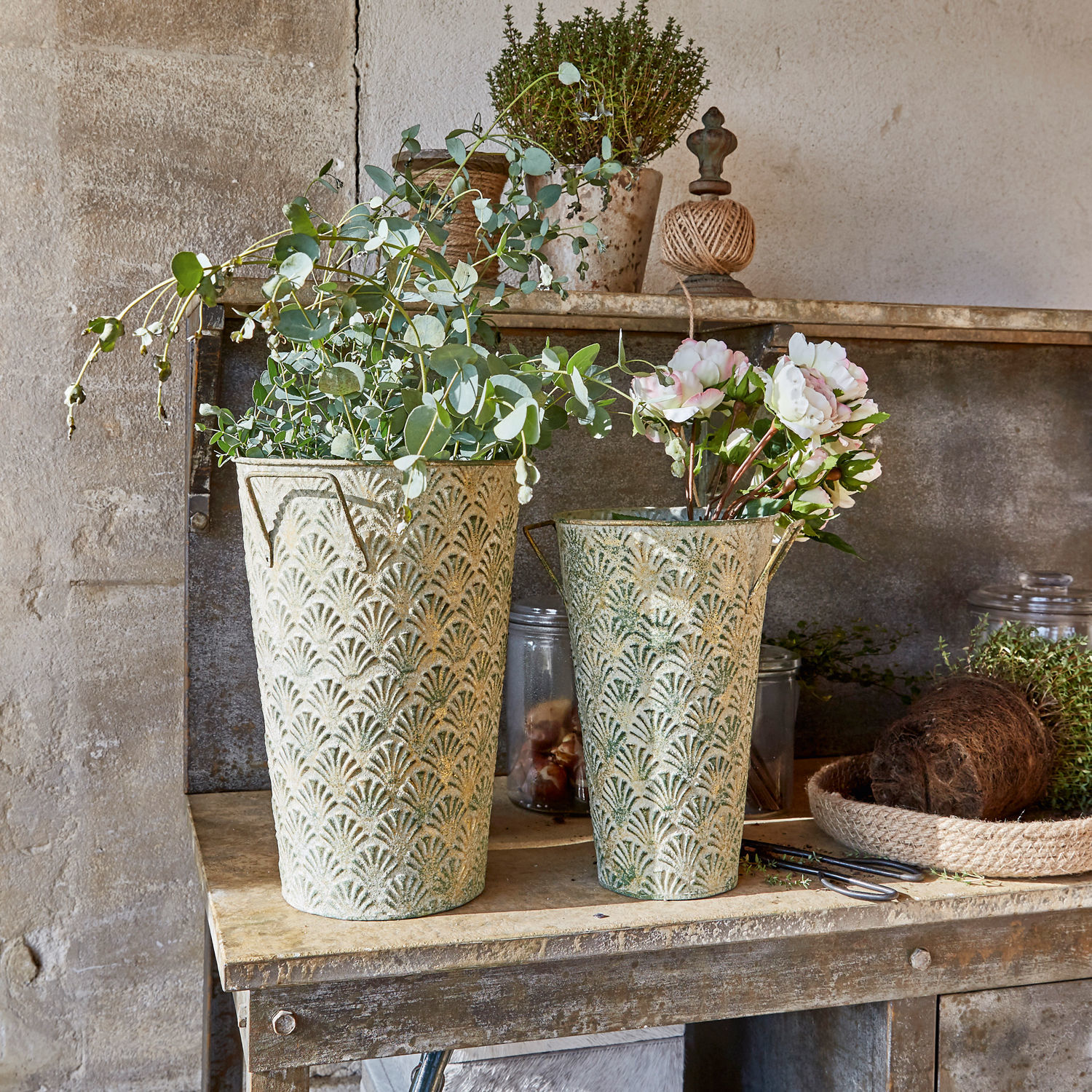 Deko-Vase 2er Set Iskele Zwei dekorative Metallblumentöpfe in Grün-Beige mit Pflanzen auf einem rustikalen Holztisch