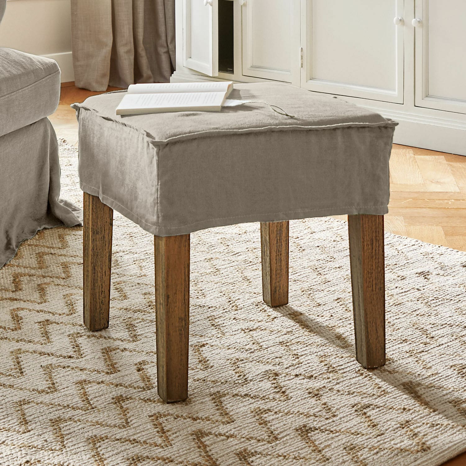 Hocker Vionnique Beiger Hocker mit Baumwollbezug und Holzbeinen auf hellem Teppich im Wohnzimmer