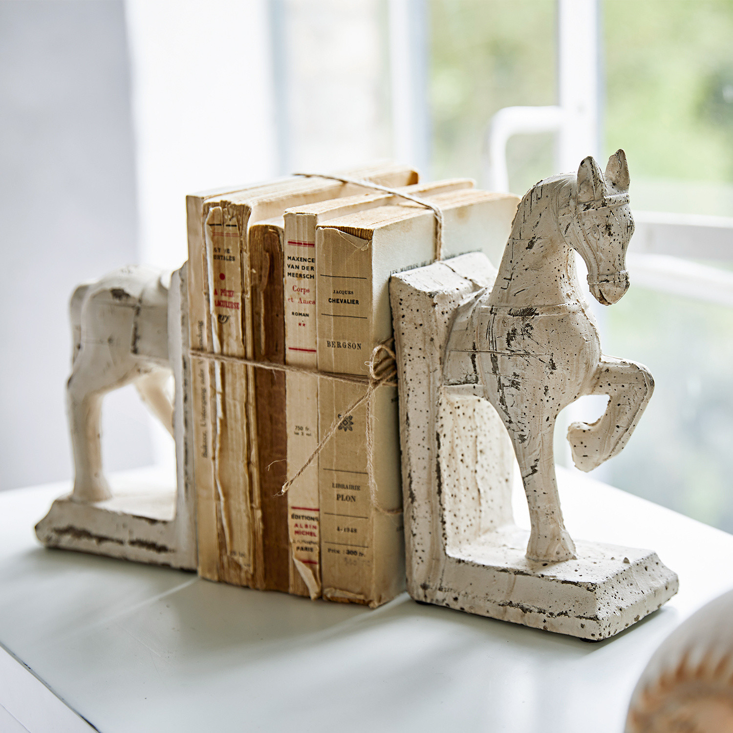Buchstütze 2er Set Horses Weisse Keramik-Buchstützen in Pferdeform mit alten, gebundenen Büchern auf einem Tisch