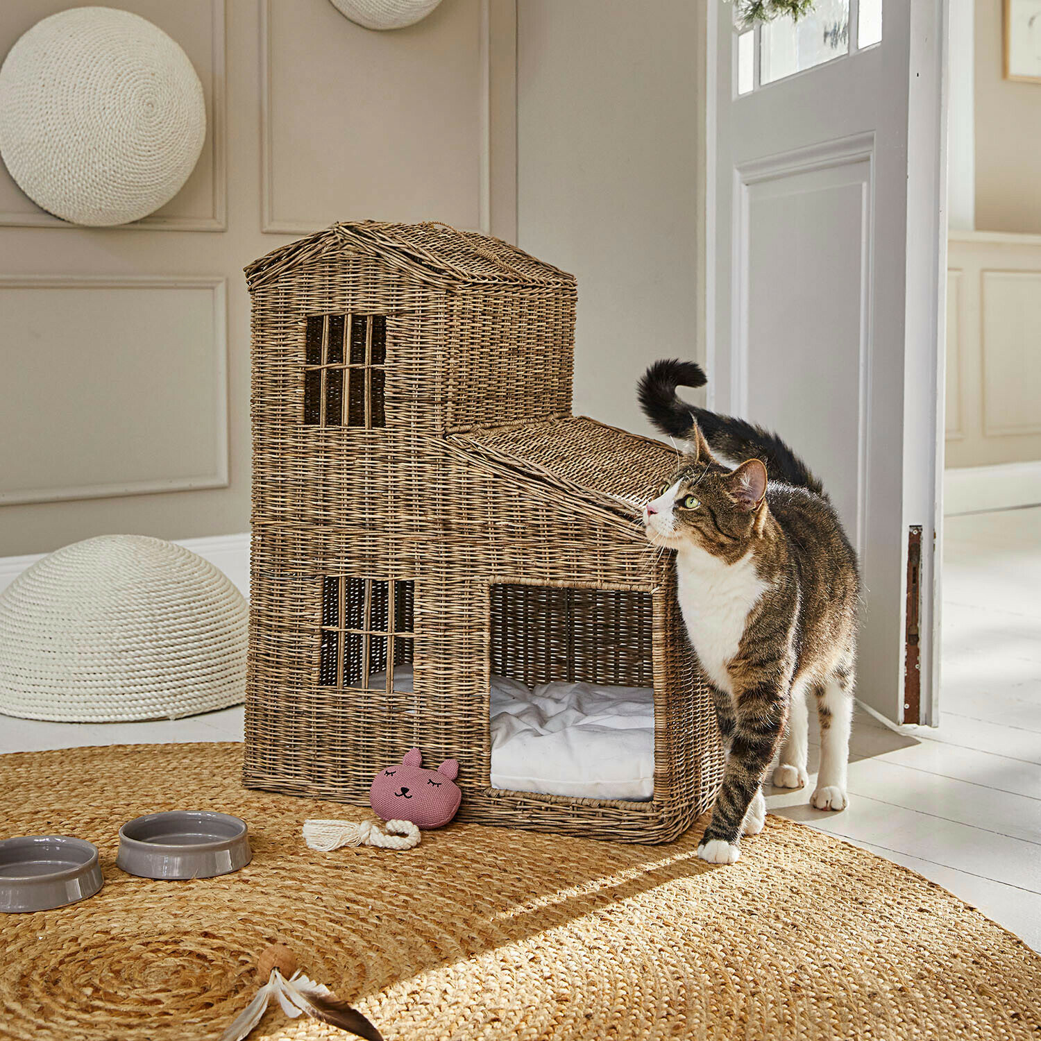 Katzenhaus Ravnda Katzenhaus aus natürlichem Rattan auf rundem Teppich mit Spielzeug und Futternäpfen