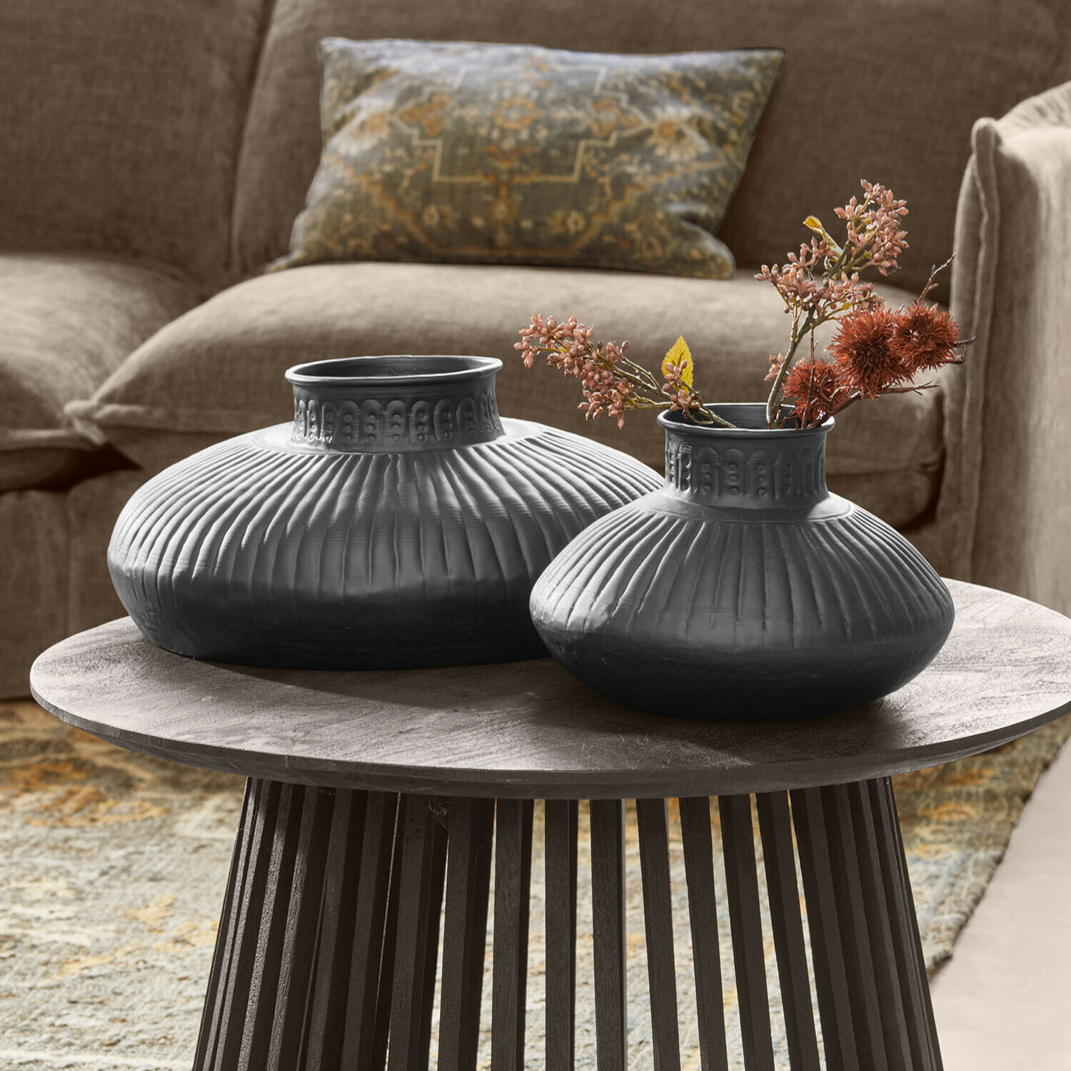 Vase 2er Set Myrkja Zwei schwarze Keramikvasen mit geriffeltem Muster auf einem Holztisch im Wohnzimmer
