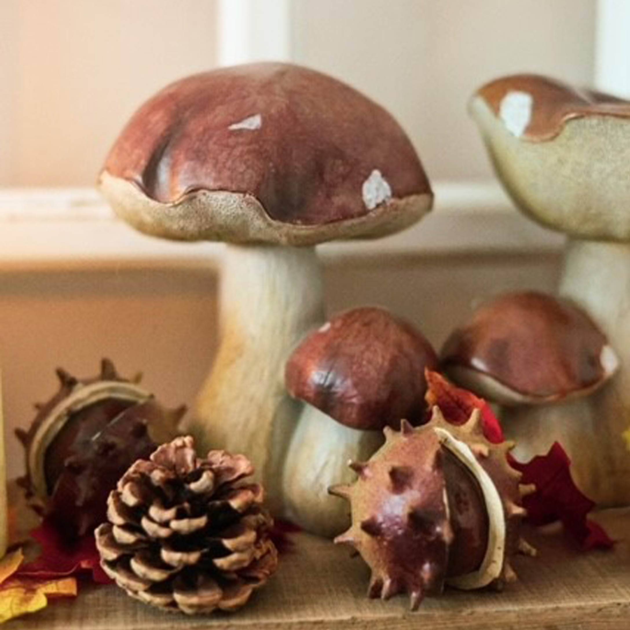 Dekorative Pilze aus Keramik in Braun-Beige mit Kiefernzapfen und Kastanien für Herbstdekoration