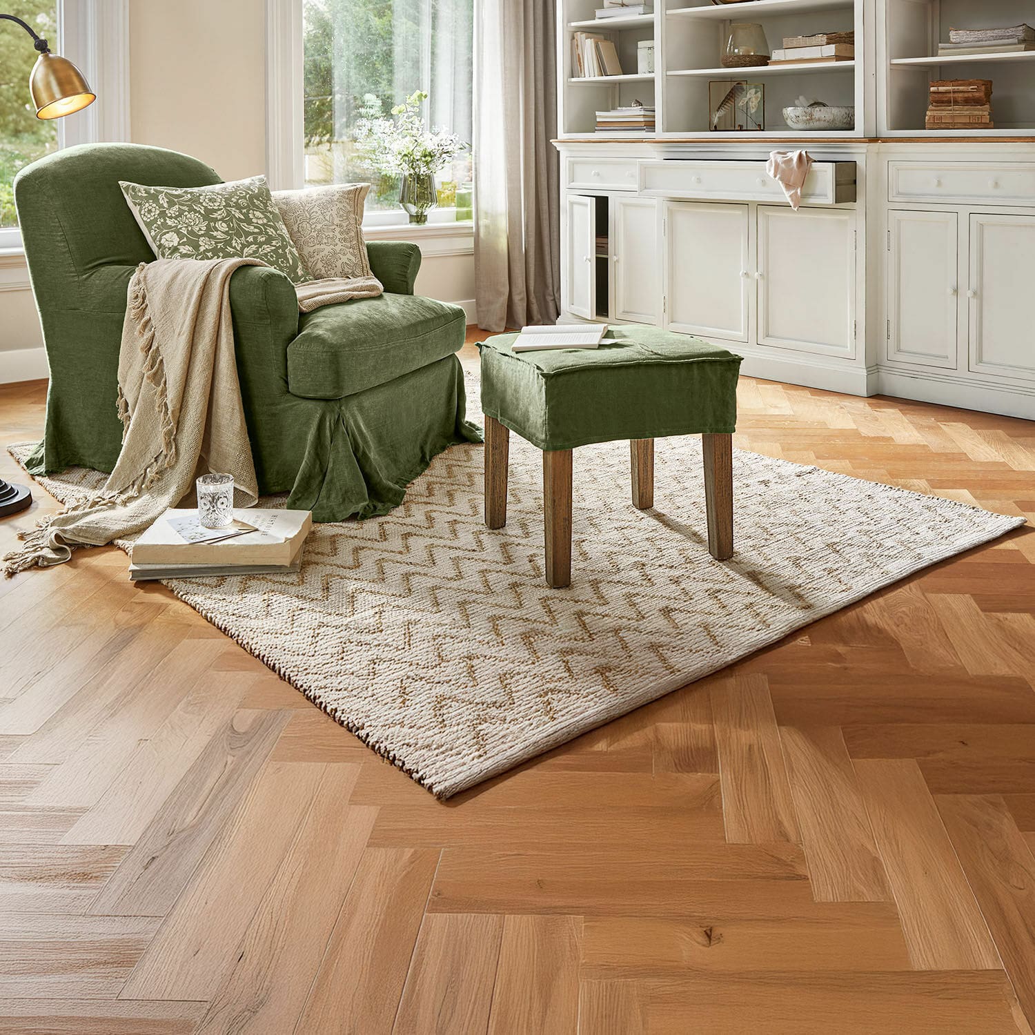 Wendeteppich Vendeline Grüner gepolsterter Stuhl und Hocker aus Stoff in einem gemütlichen Wohnzimmer mit Teppich und Holzboden