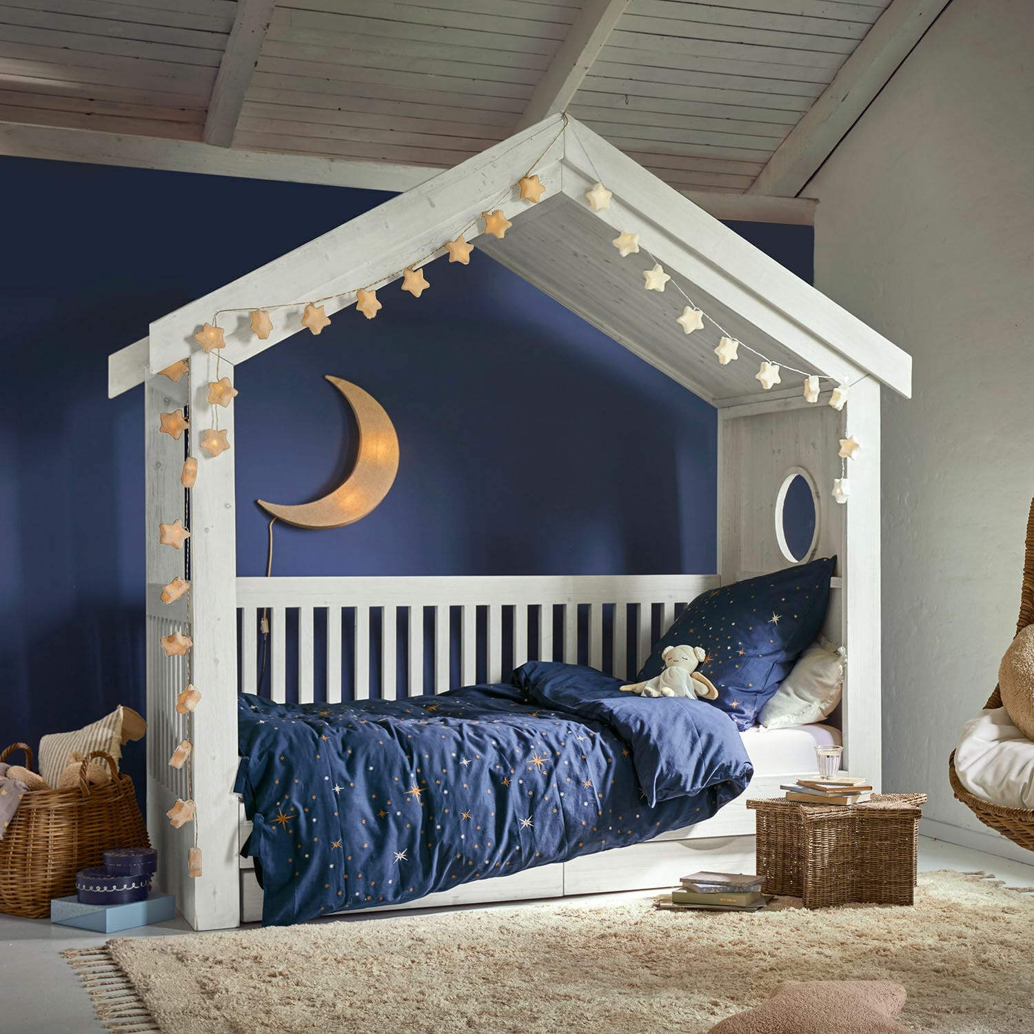 Einzelbett Birchwell Weisses Kinderbett aus Holz in Hausform mit dunkelblauer Sternenbettwäsche und Mondlampe