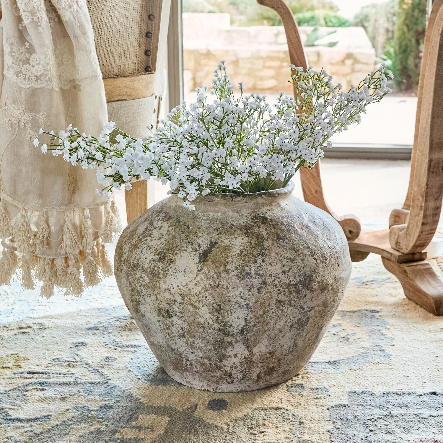 Vase Champs Große rustikale Keramikvase mit weißen Blumen auf Teppich in hellem Raum
