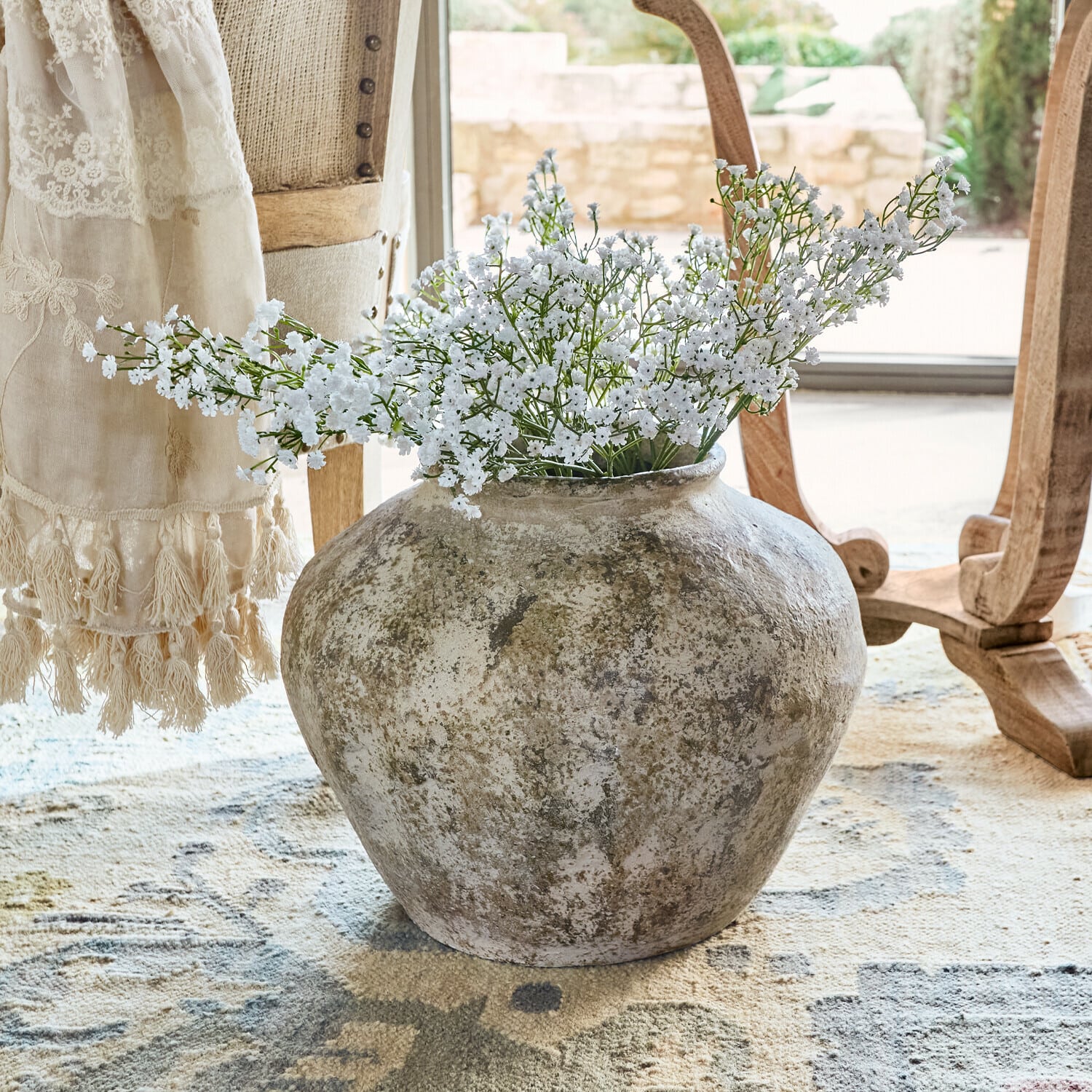 Vase Champs Große rustikale Keramikvase mit weißen Blumen auf Teppich in hellem Raum