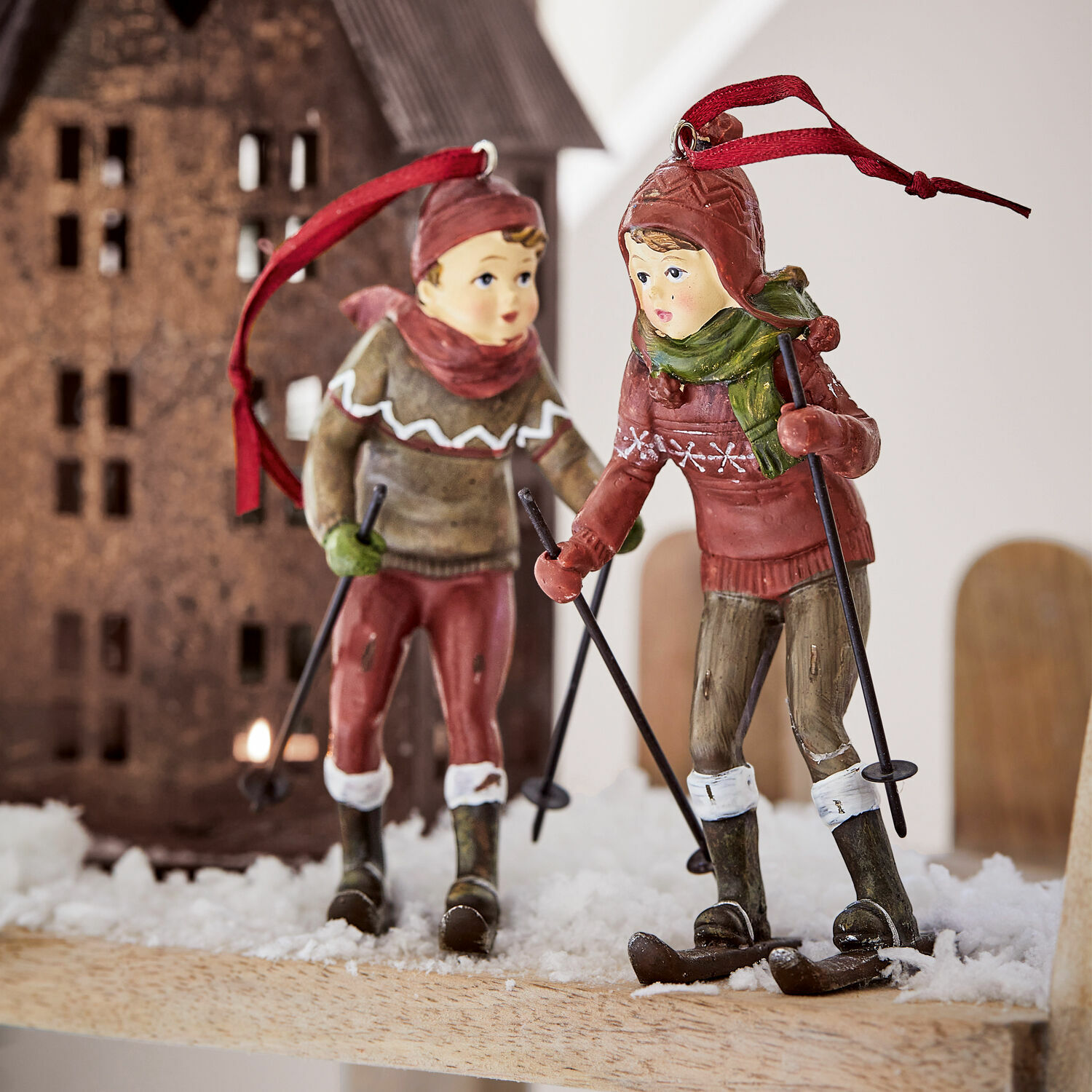 Figur 2er Set Gulbin Zwei Skifahrer-Dekorationen aus Kunststoff in roten und grünen Kleidern auf Kunstschnee.