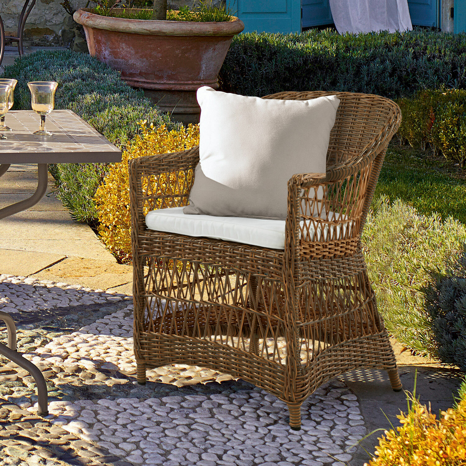 Sessel Garden Grove Rattansessel mit weissem Kissen auf Steinboden im Garten für Gartenmöbel