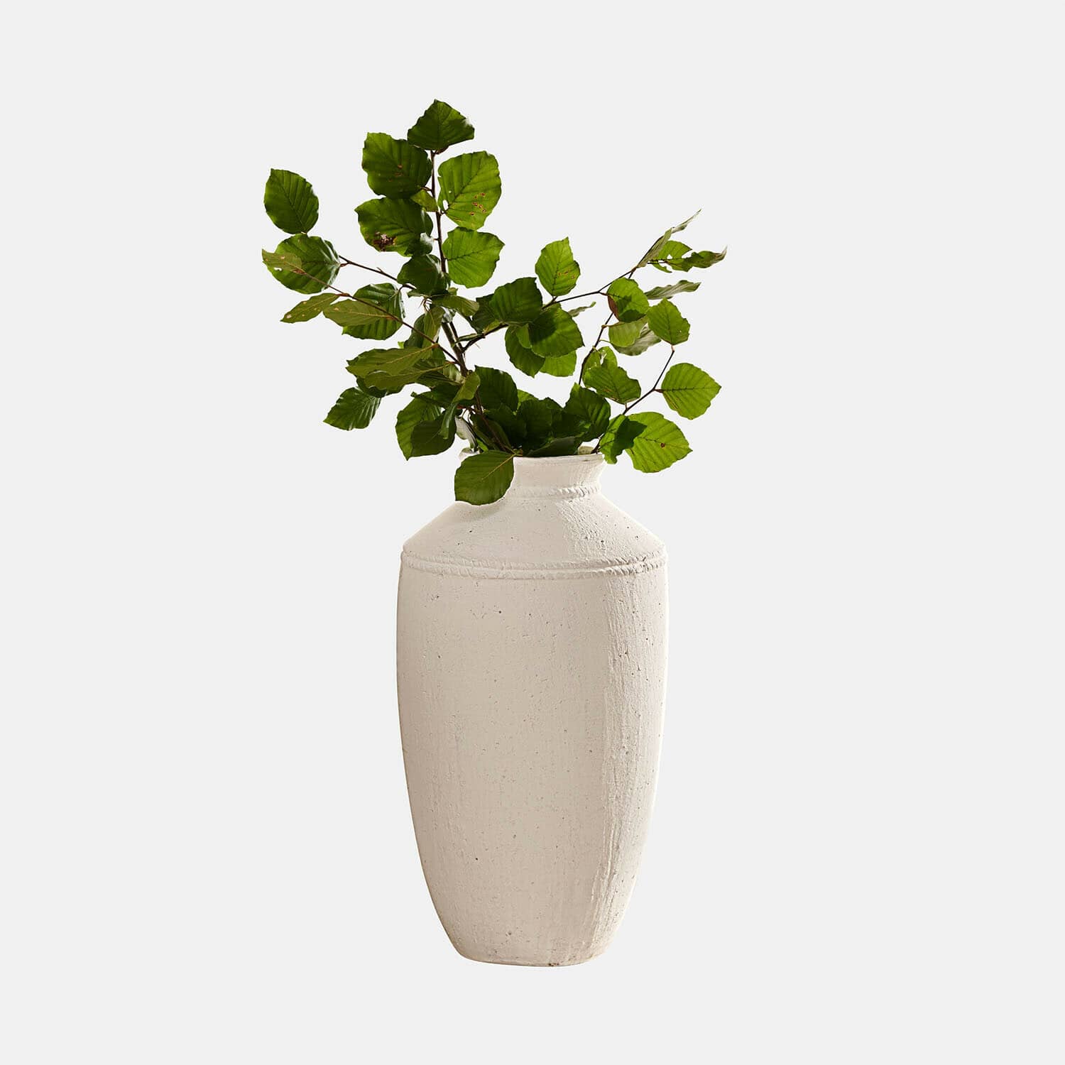 Weisse Keramikvase mit grünen Blättern, dekoratives Wohnaccessoire für modernes Ambiente