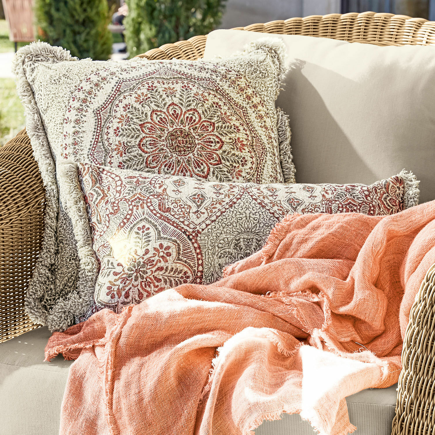Kissenhülle 2er Set Margret Beidseitige Baumwollkissen mit beigem und rotem Muster sowie orangefarbene Decke auf Rattansofa