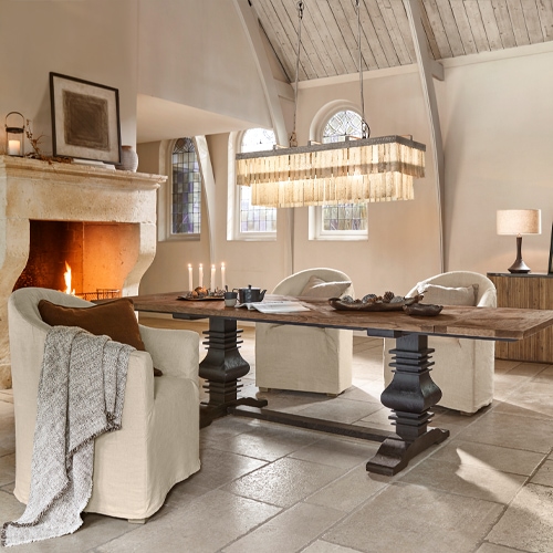 Esszimmer mit rustikalem Holztisch und cremefarbenen Polstersesseln am Cheminée, gemütlicher Stil