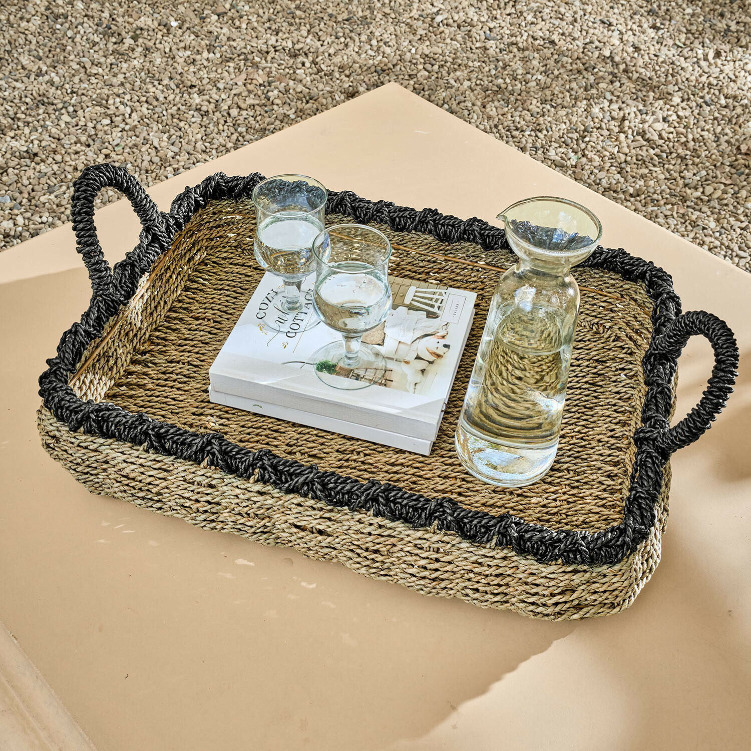 Rechteckiges Tablett aus geflochtenem Seegras mit schwarzem Rand und Griffen, mit Karaffe und Gläsern auf Tisch