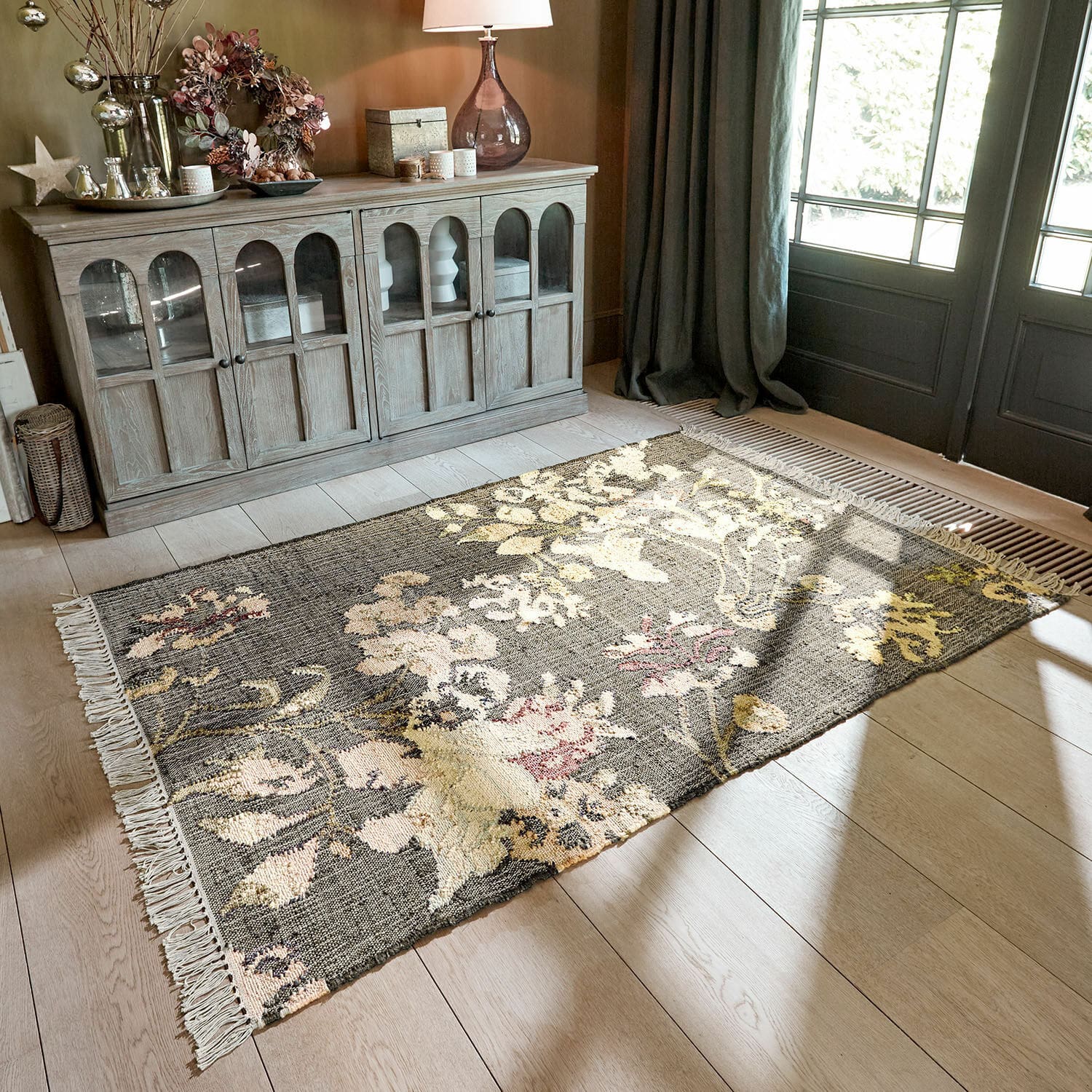 Teppich Yasirah Blumenmusterteppich in Grau- und Cremetönen auf hellem Holzboden im Wohnzimmer