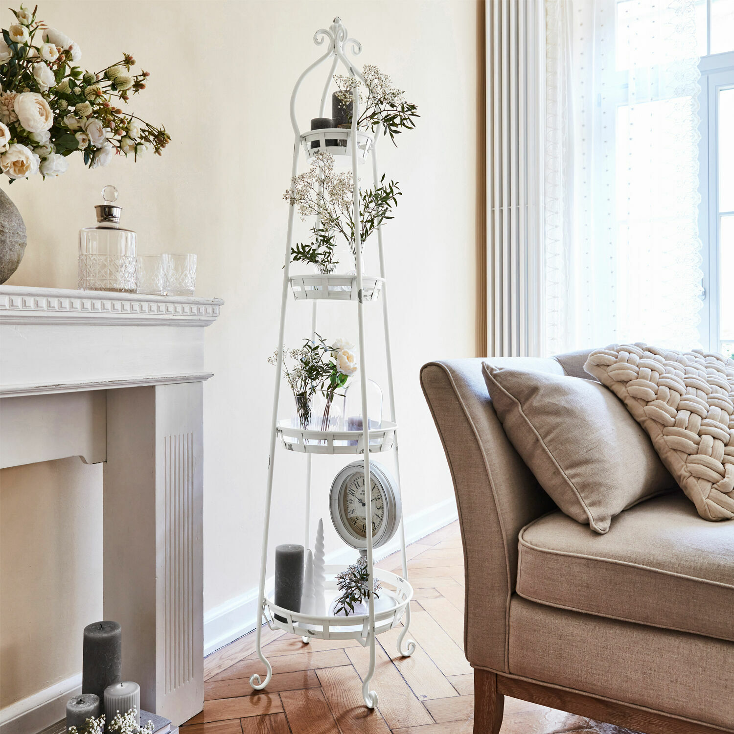 Etagere Ipas Weisses Metallregal mit Ablagen und Blumenarrangements im hellen Wohnzimmer mit beigem Sofa