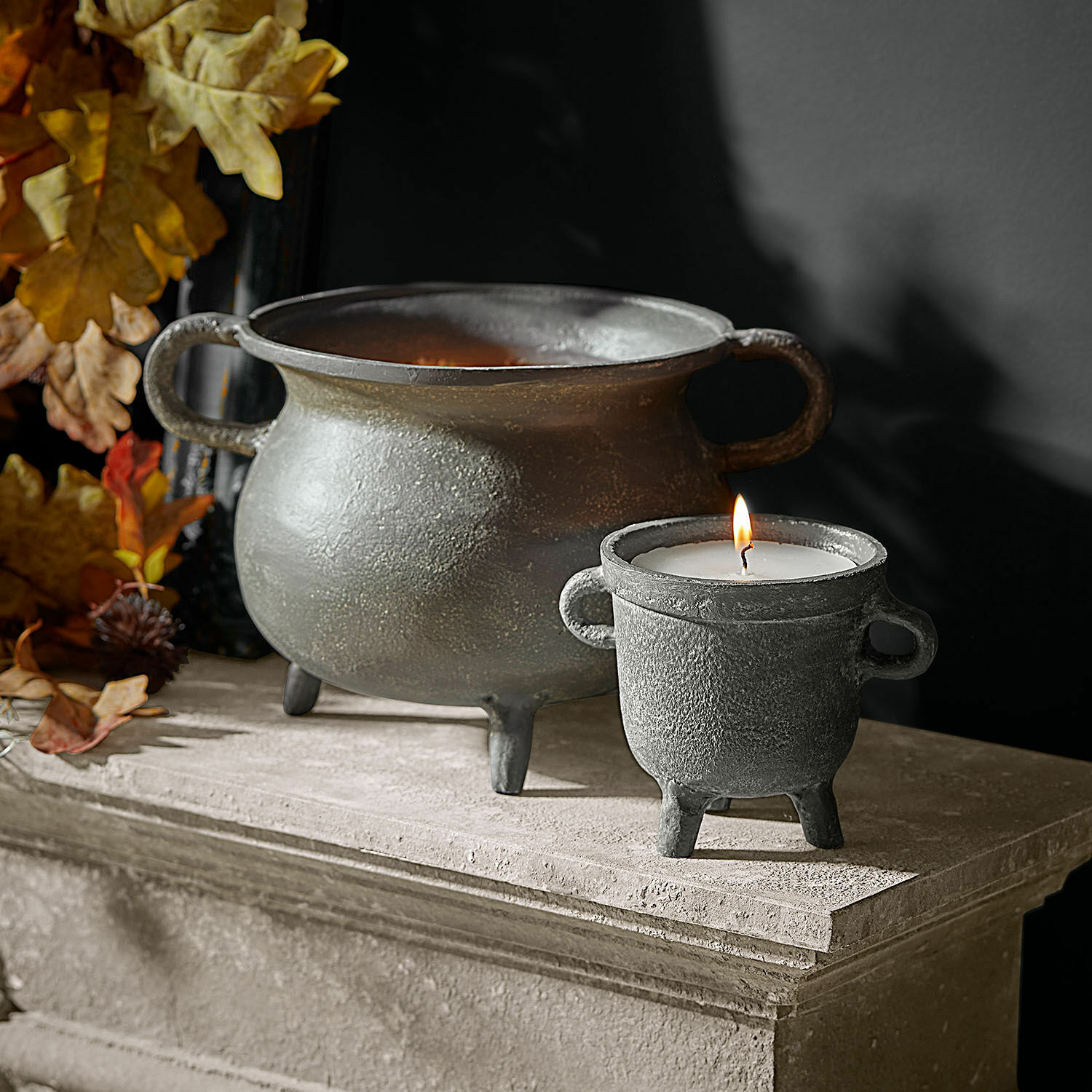 Windlicht mit Kerze 2er Set Lavignoux Dekorativer Kerzenhalter und Schale aus grauem Metall auf steinerner Ablage mit Herbstlaub.